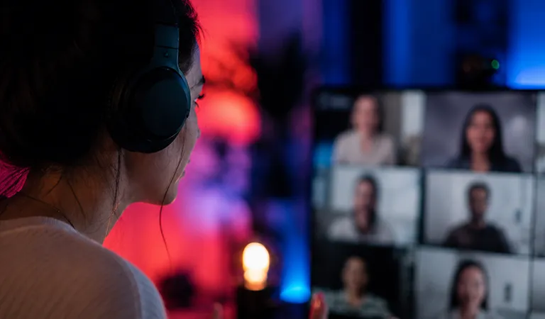 Person wearing headphones attending an online video conference, representing Cyber Security Webinars and cyber awareness training for businesses, with multiple participants displayed on a virtual meeting screen.